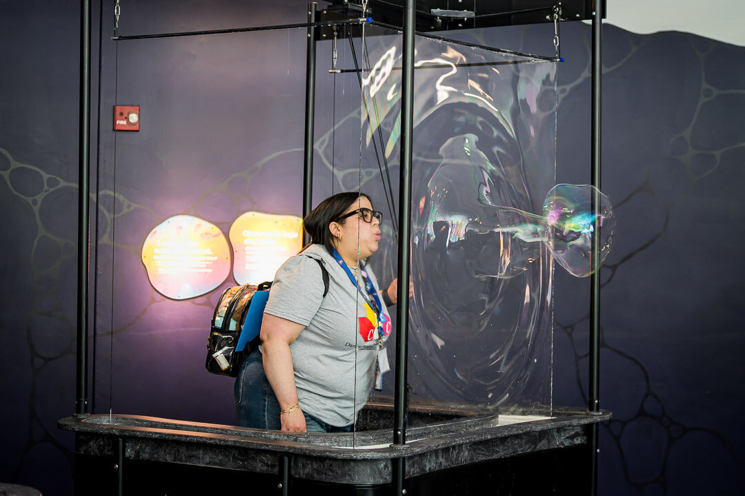 Corporate event photography of woman engaging with interactive science exhibit during business conference new york.