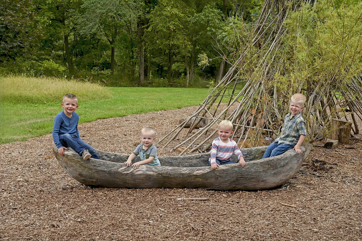 4 happy boys sit in a canoe for their Iowa Family Portraits
