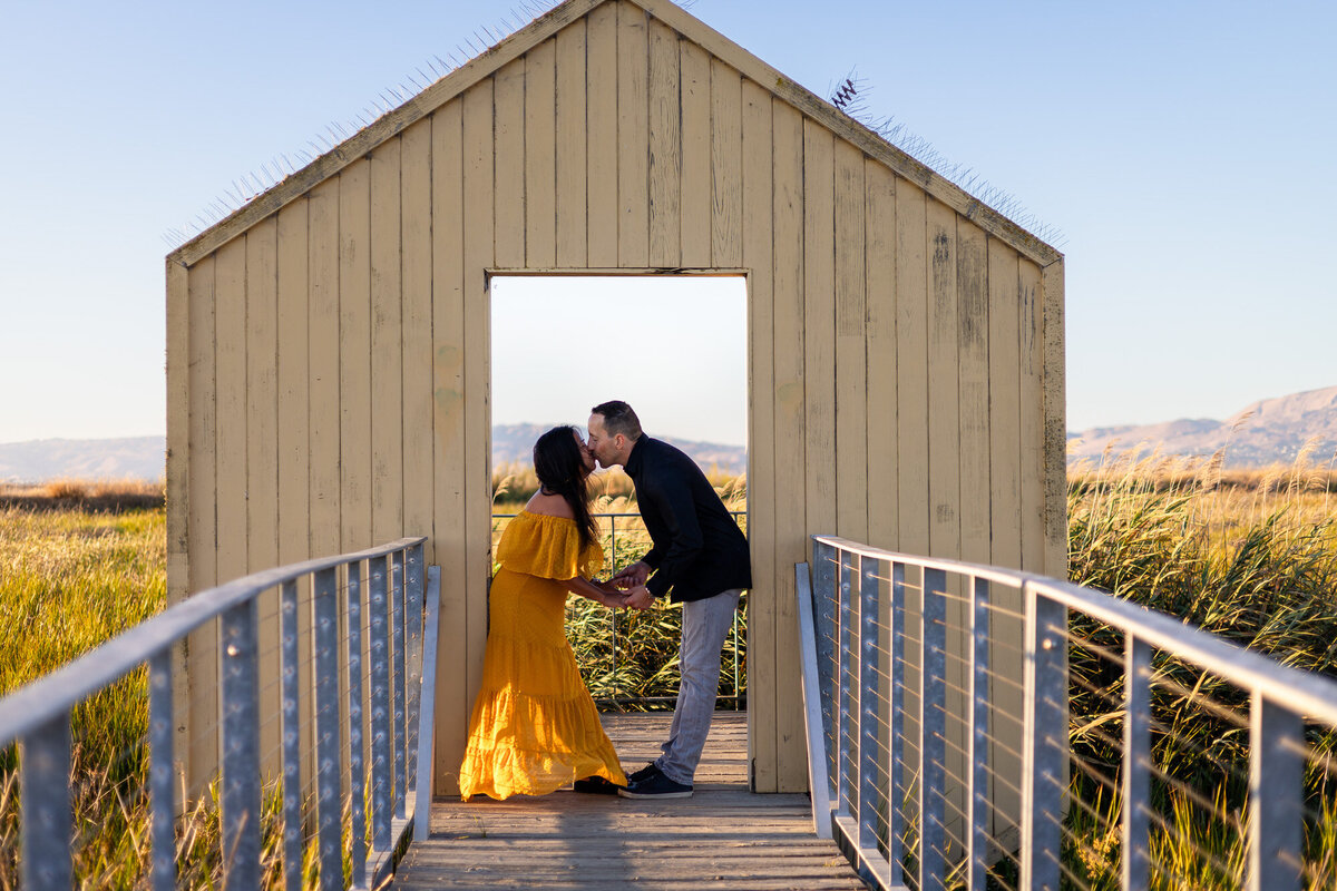 Couple kissing in a wooden doorway during golden hour at a scenic marsh – Bay Area Couples Photography Portfolio - Ellobelle Photography