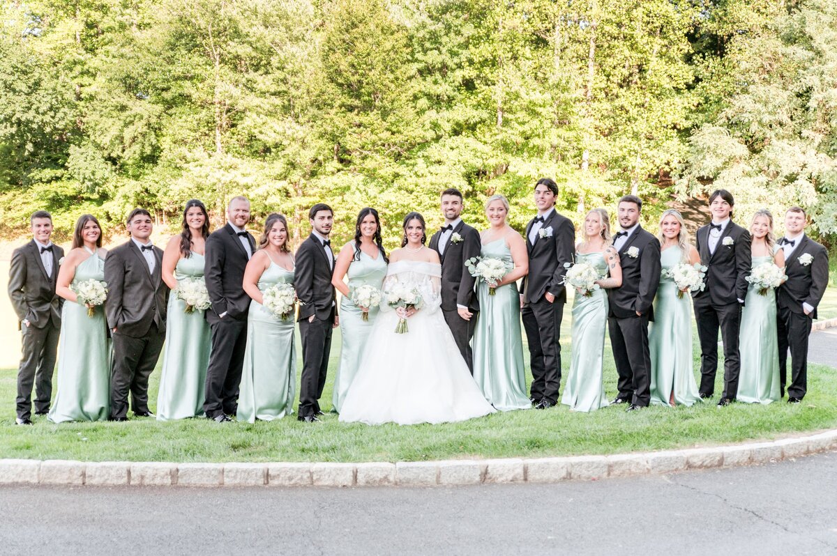 wedding party in sage green dresses ans black tuxedos on golf course