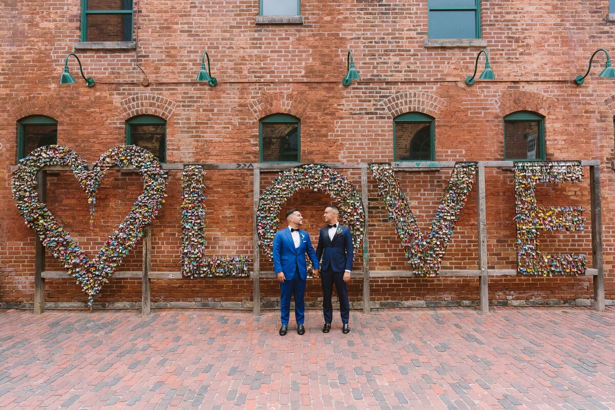 groom and groom kissing in front of love sign