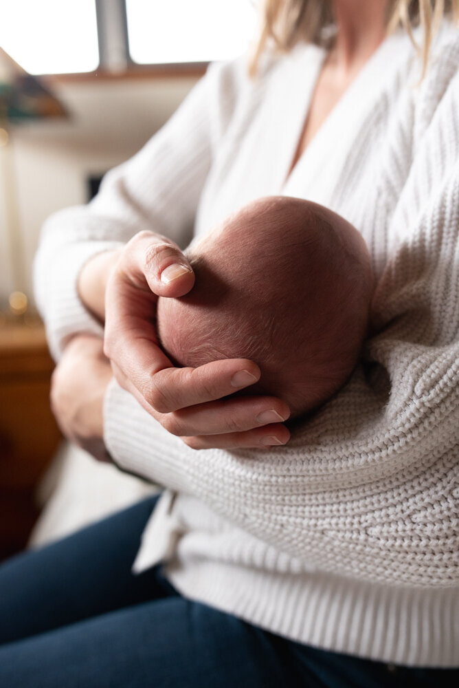 Close up view of baby's head and hair cradled in his mom's hand
