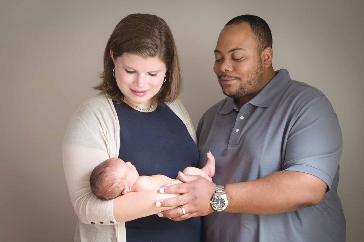 New mom and dad looking at newborn son during in home newborn session in Columbia SC