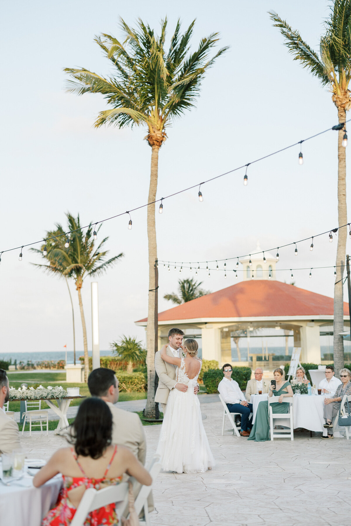 Bride and groom share their first dance beneath twinkling lights at their destination wedding in Cancun, Mexico.