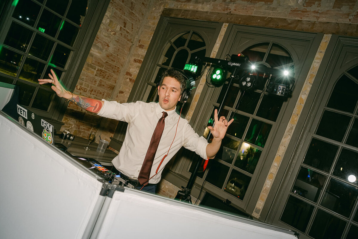 Luxury DJ booth with red tones and dramatic flash lighting at Texas wedding party