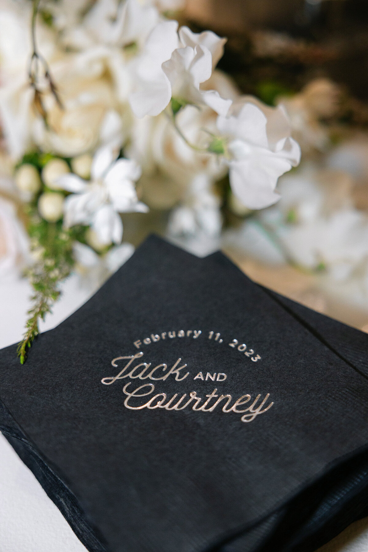close-up of wedding napkins personalized with the couple’s names and floral accents at The Adolphus in Dallas, highlighting thoughtful and elegant reception details.