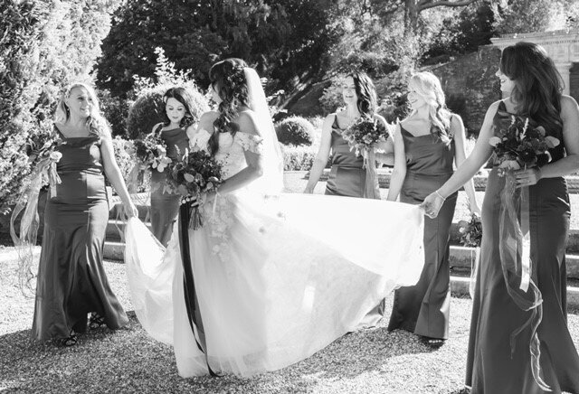 Bridesmaids lifting the brides train helping her wlak with her dress