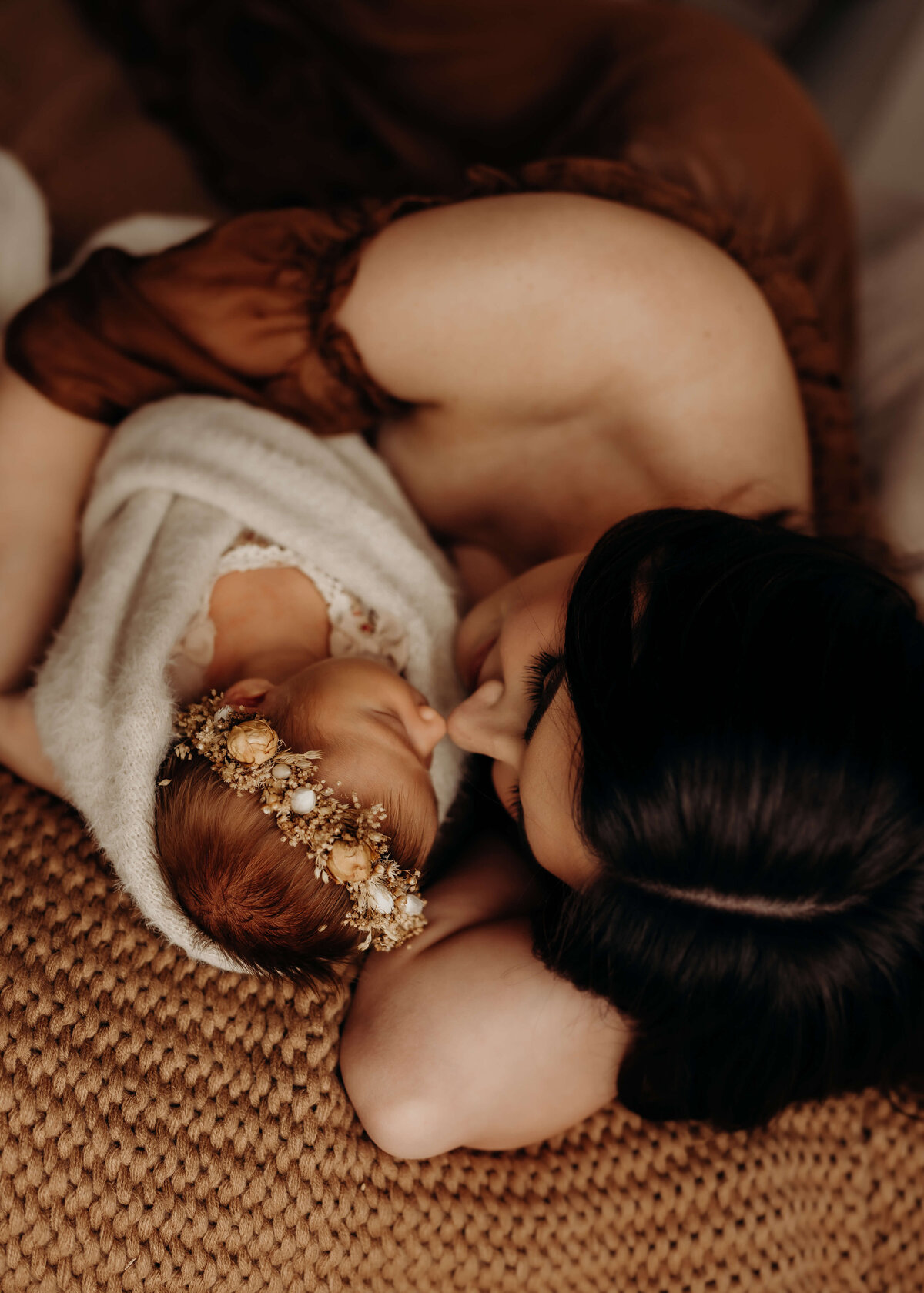 newborn mom holds infant girl close in brown gown