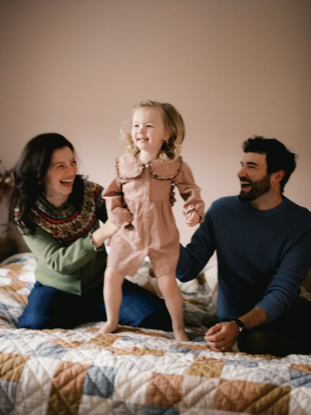 huntsville couple watches daughter jump on bed smiling and laughing at huntsville alabama photography session