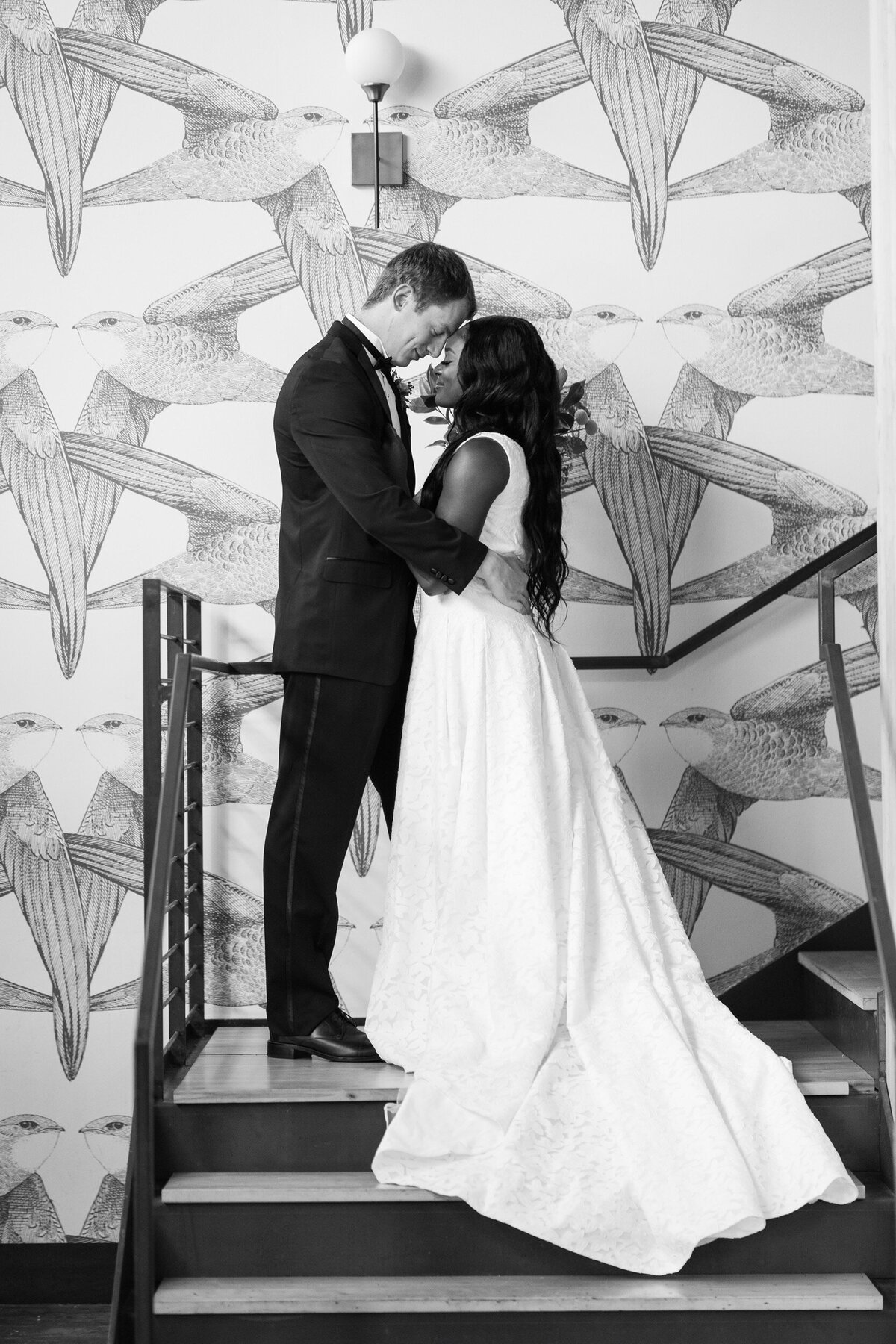 A black and white photo of a bride and groom on the stairwell at their Raleigh wedding.