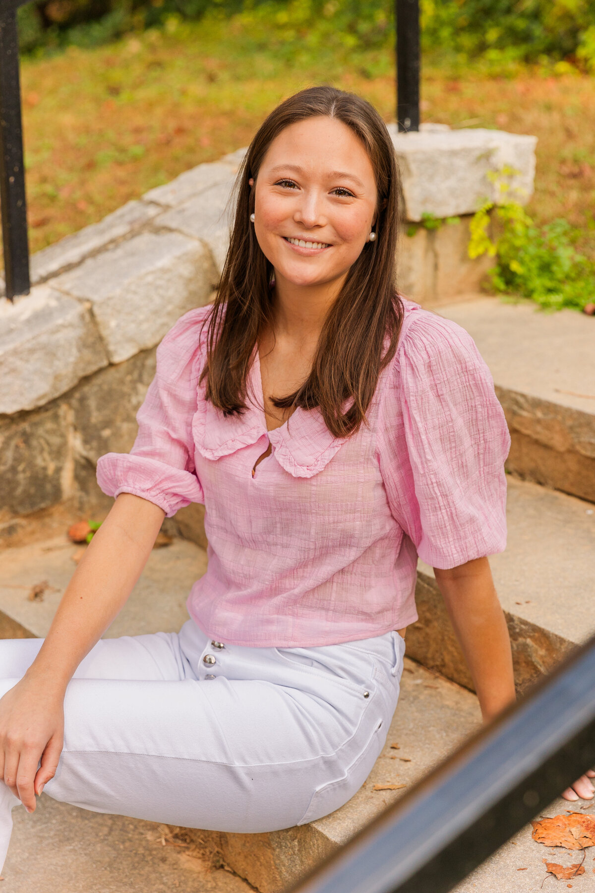 teenager girl sitting sideway on park stairs looking at the camera leaning on one hand