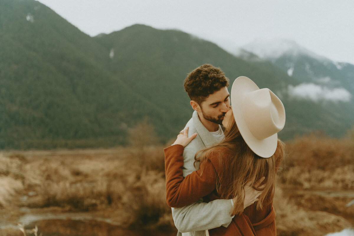 romantic photo of a girl and boy dancing in front of the mountains