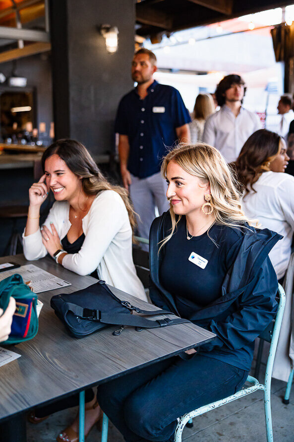 Two girls laugh and smile while sitting at a restaurant.