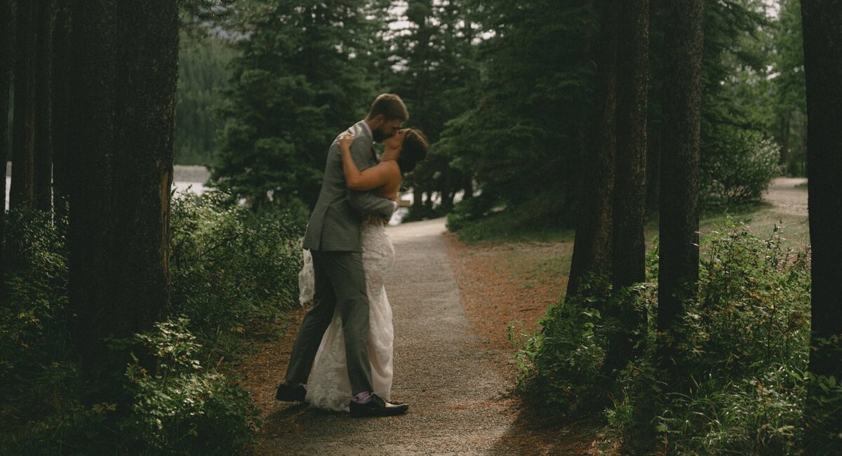 Wedding couple dance and kiss in trees in mountains