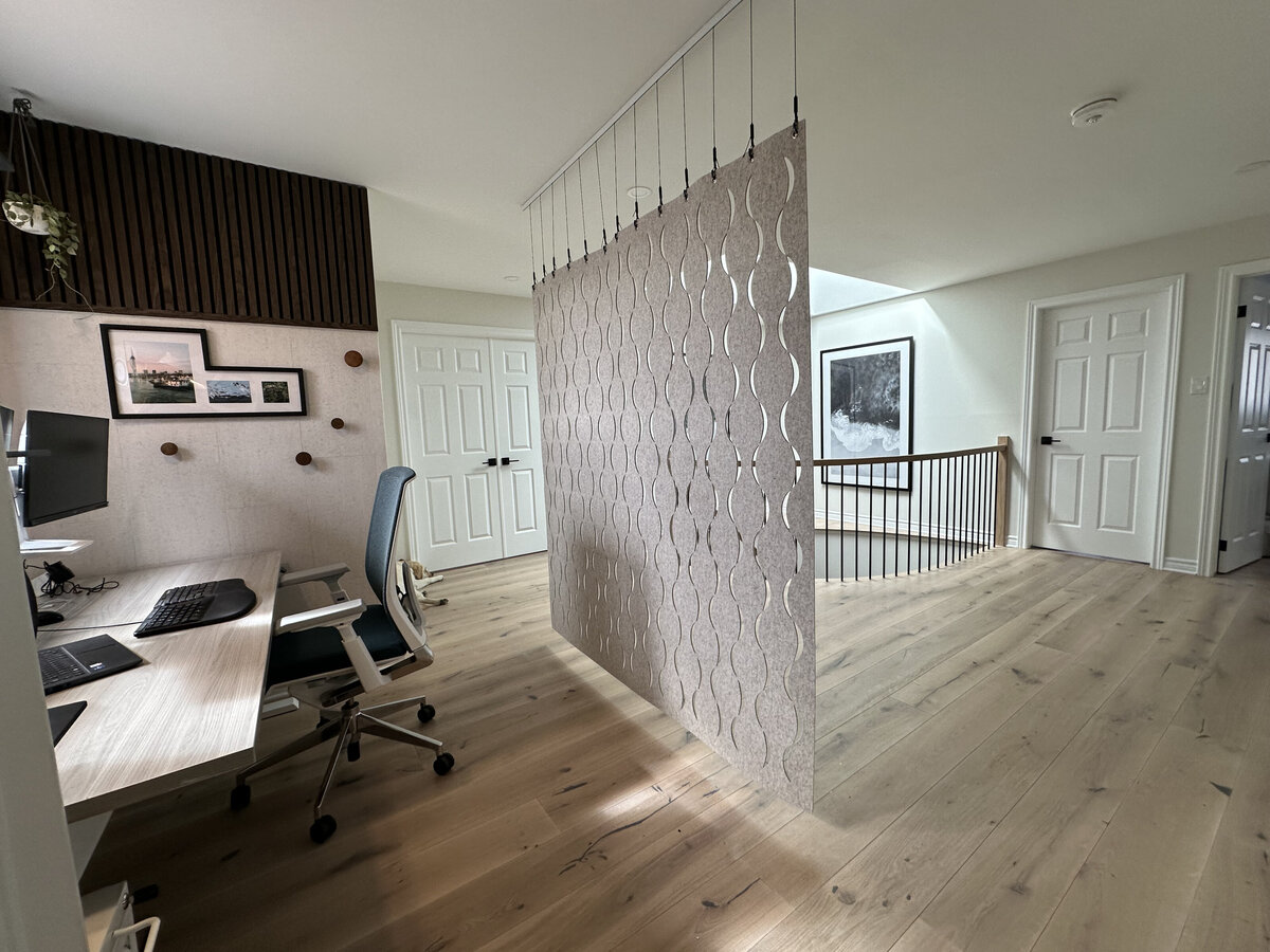 A spacious landing offers room for a small home office space, which is separated by a hanging grey felt divider in Barrhaven On