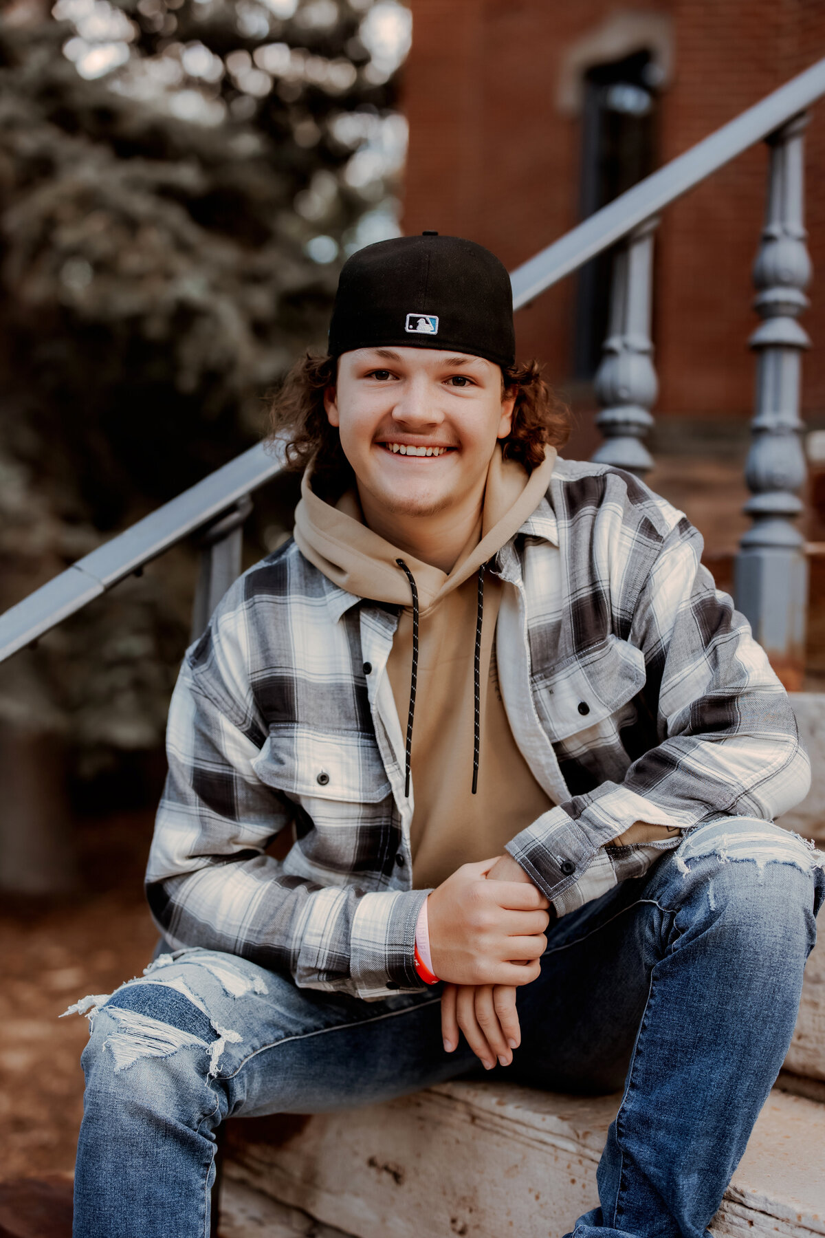 boy sits with back against stairs in boulder colorado for senior session