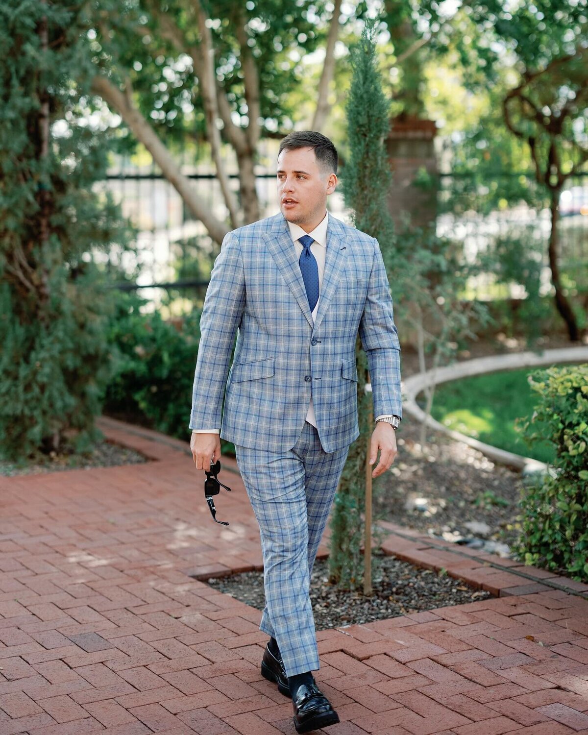 A man wearing a bold, patterned type of suit struts outside