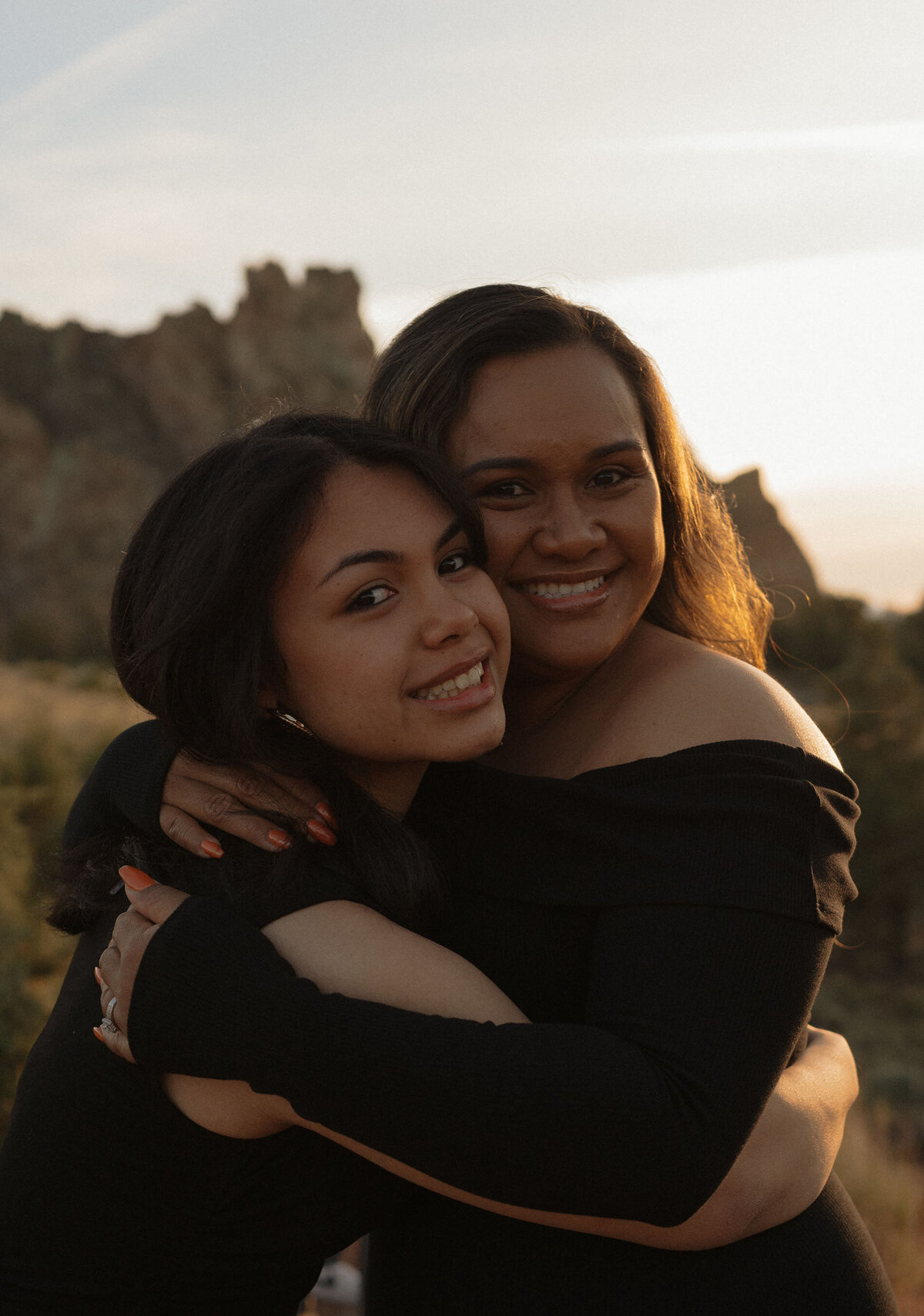 mother and daughter smiling and hugging during golden hour at Smith Rock State Park