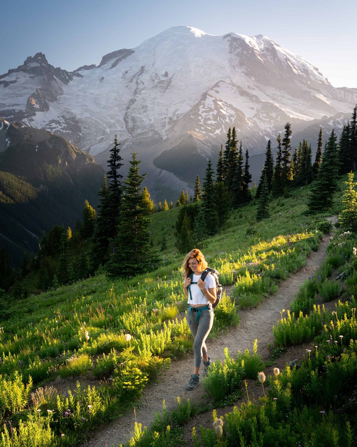 Jess of Jess Wandering walking on a path surrounded by grass and pine trees with mountains in the background