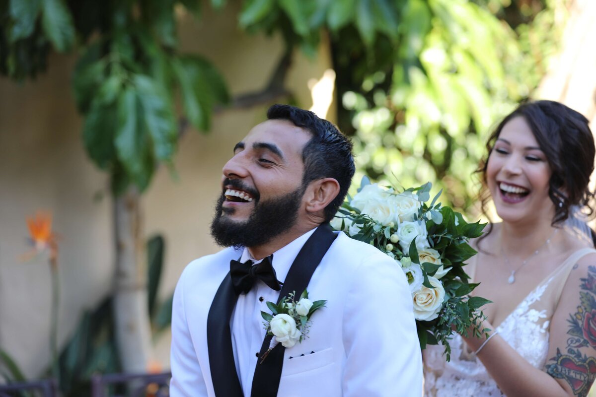Newport Beach wedding photographer first look of bride surprising groom while he laughs