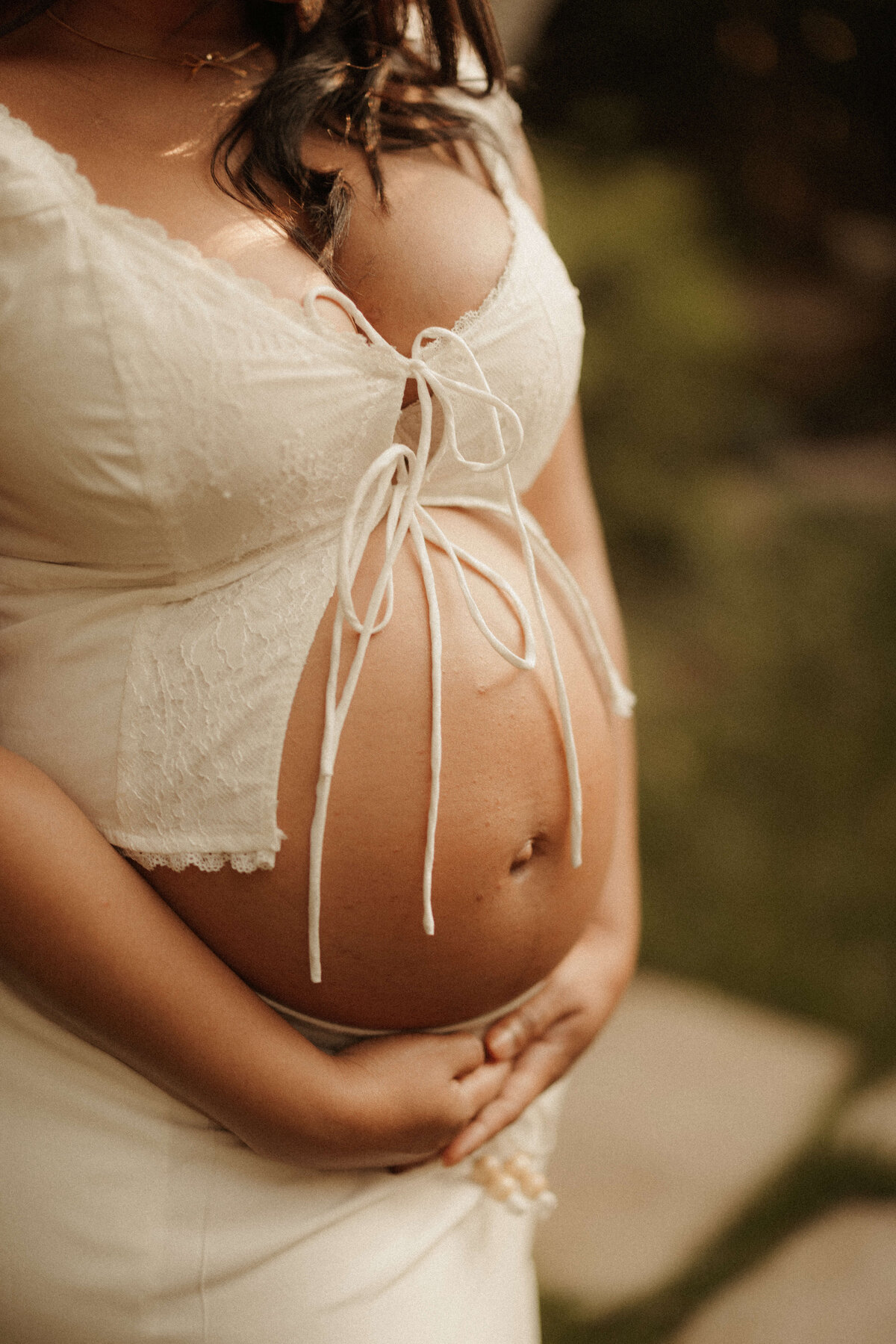 Pregnant woman holding bump in flowing dress during Franklin Tennessee outdoor maternity shoot