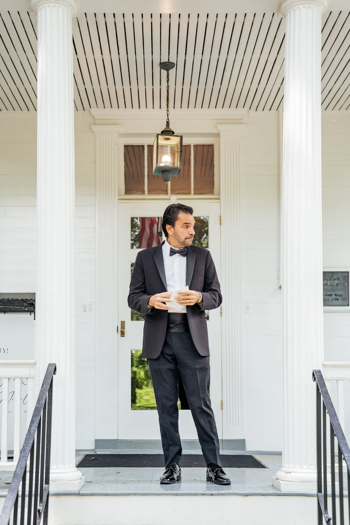 Father reading a letter from bride on the porch of Haywood Hall in Raleigh, NC