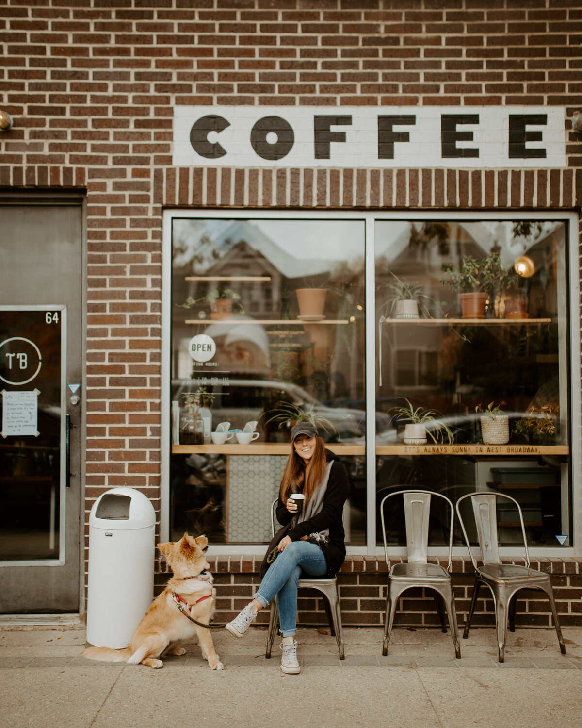 woman smiling and drinking coffee with her dog beside her
