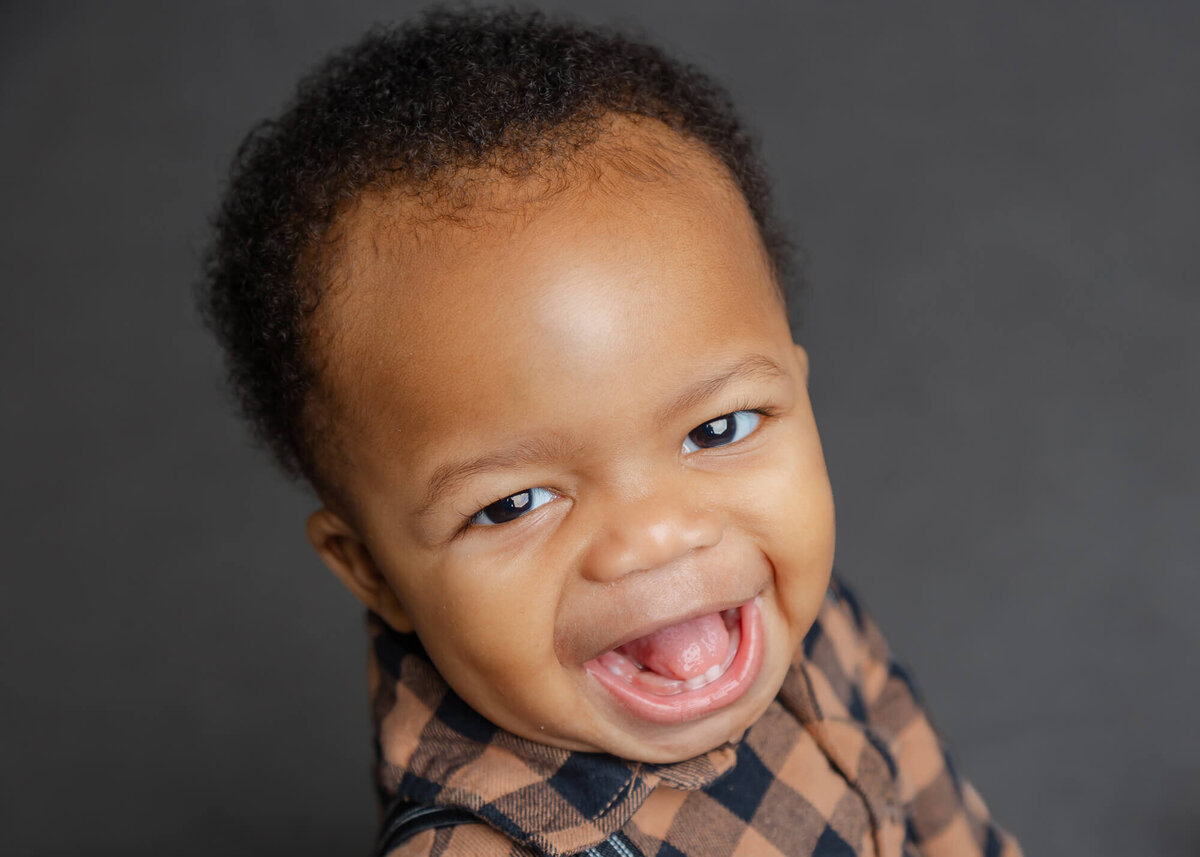 Happy African American Infant boy in a brown and black plaid shirt smiling in his school picture by Jessica Bowles