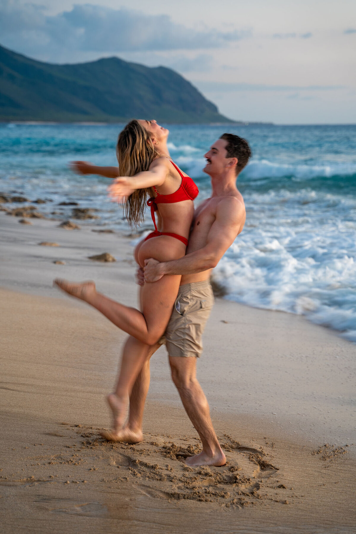Couple playing on the beach for Hawaii engagement photography session