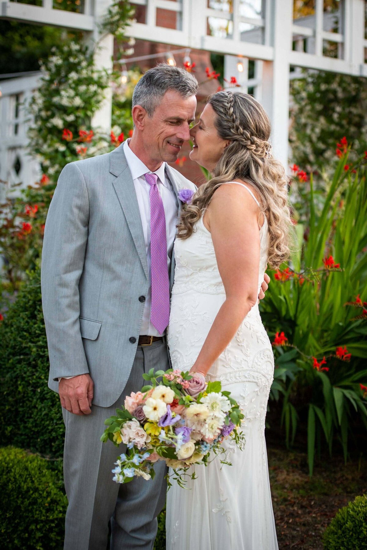 Bride and groom smiling and she holds her beautiful summer bouquet.