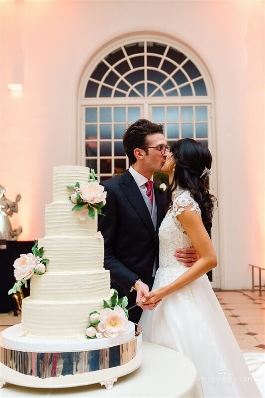 Lila & Davide kissing after cutting their wedding cake.