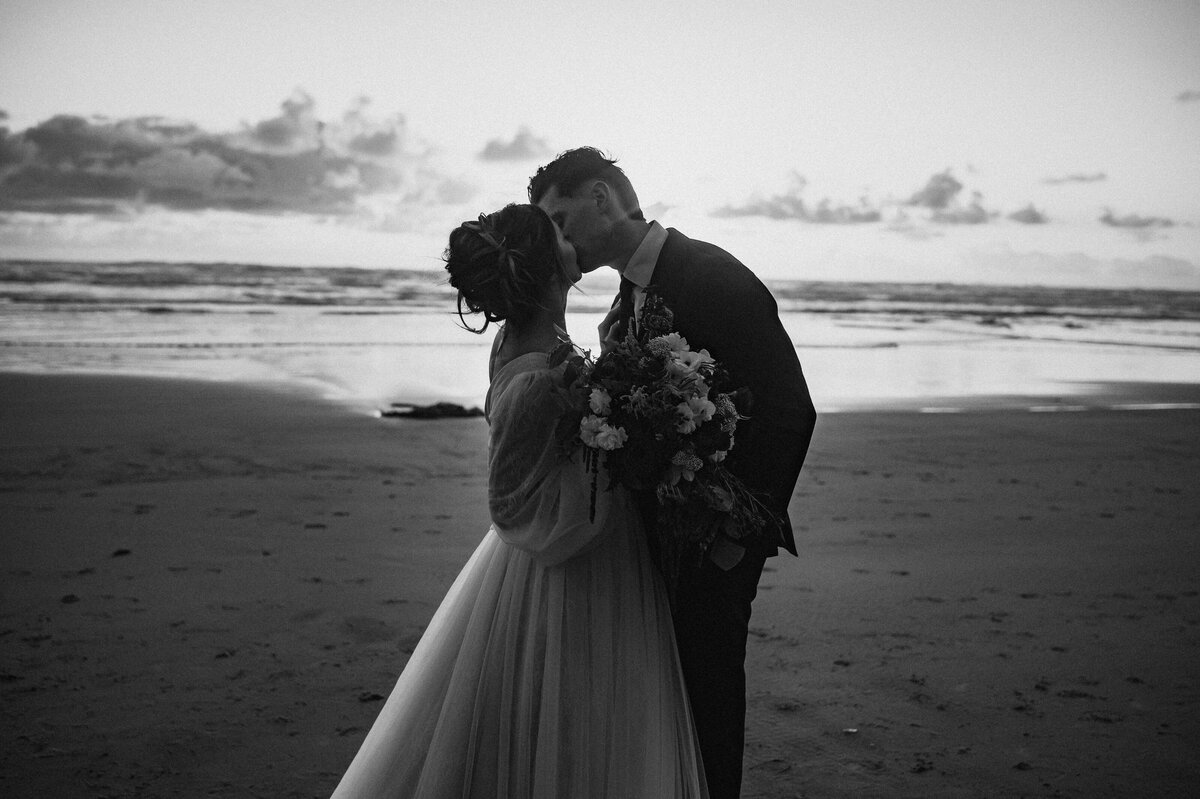 Newlywed couple kissing on beach