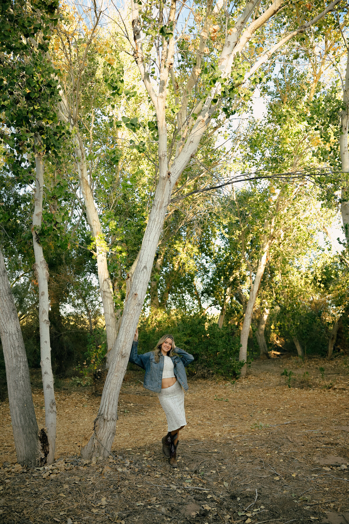 Golden Hour Senior Portrait of Teen Girl in Field Wearing Casual Red Top and Denim Jeans