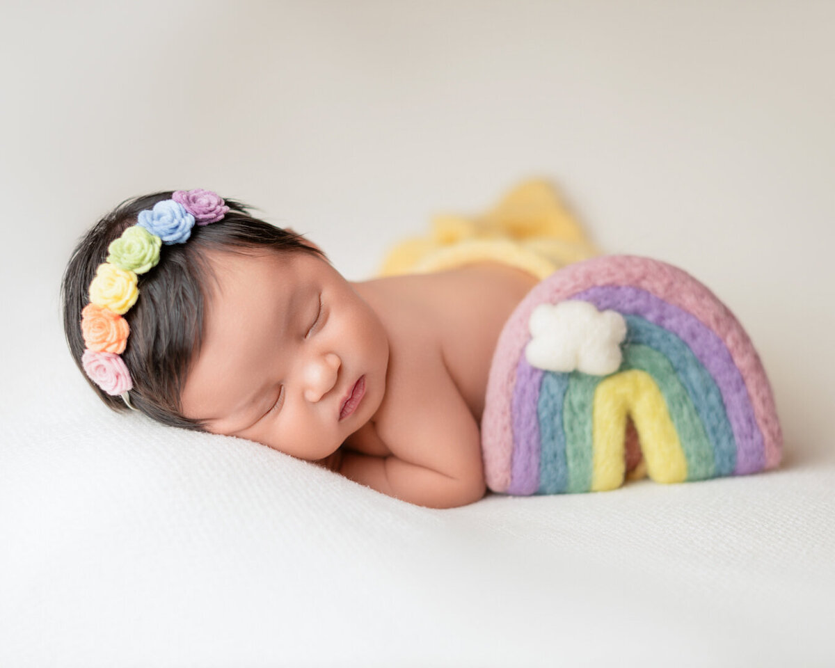 Newborn baby wrapped in soft rainbow blanket – vibrant Houston photoshoot by Lissette G.