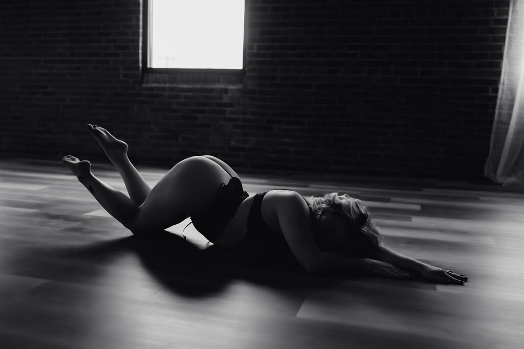 black and white portrait of woman on bed in boudoir sheets