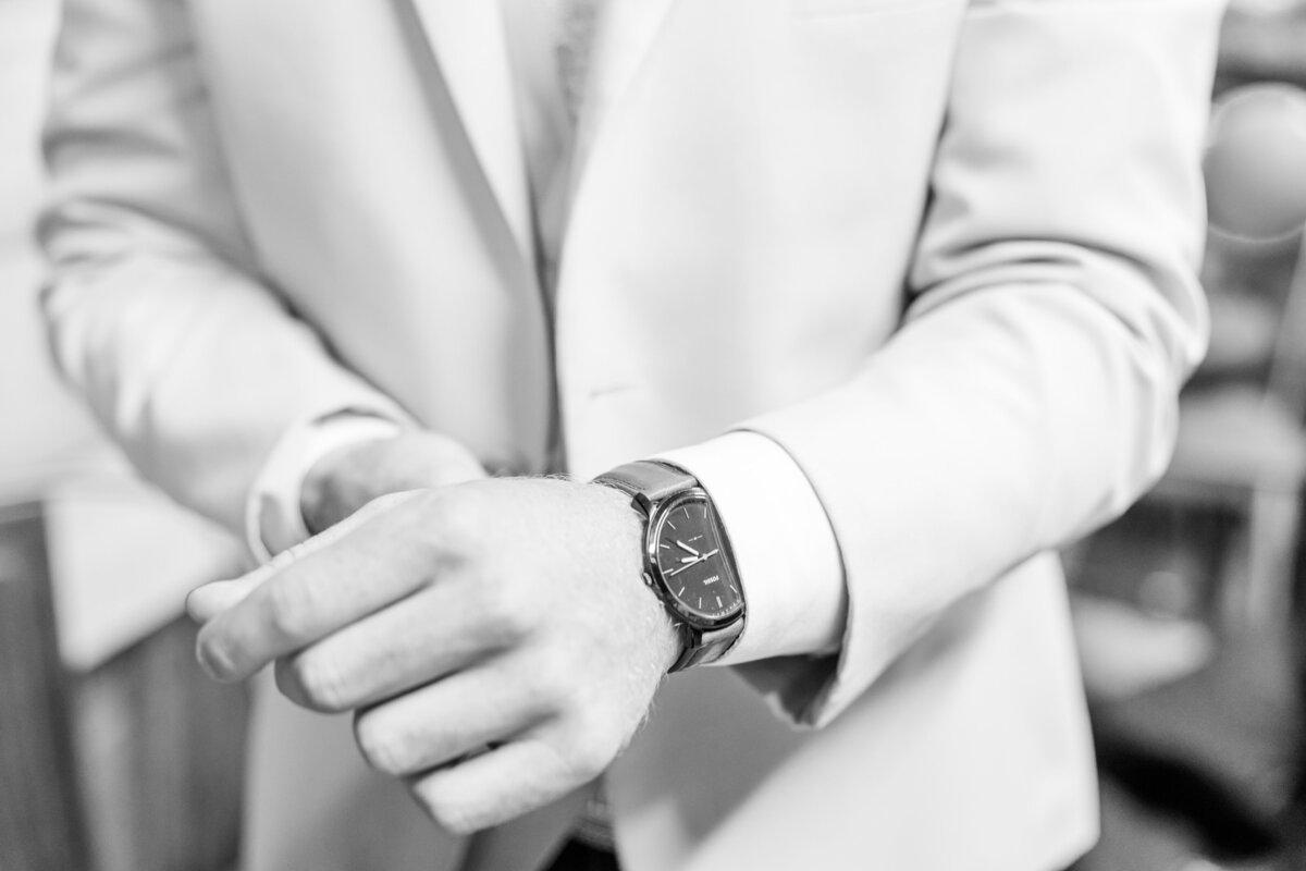 groom buttoning his shirt with details of his watch