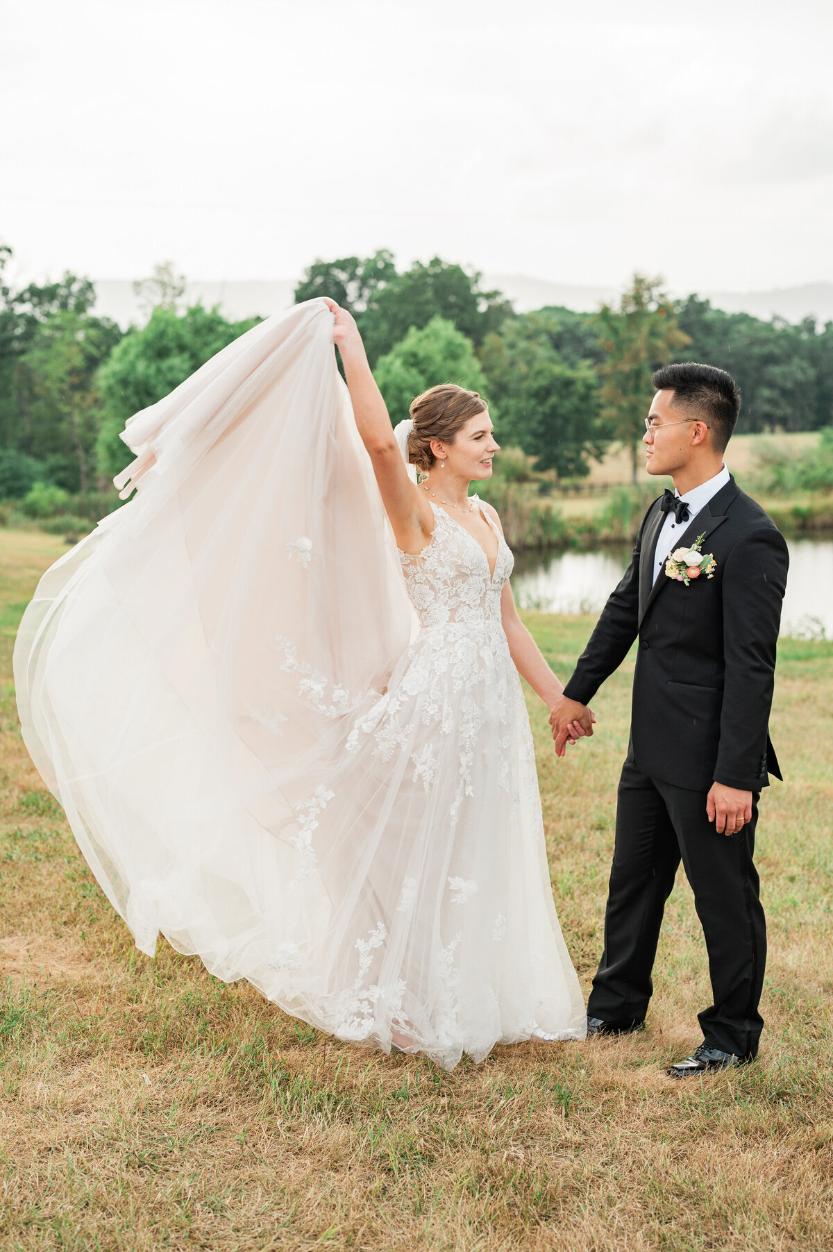 A bride holding up the back of her dress with one hand and her partner's in the other