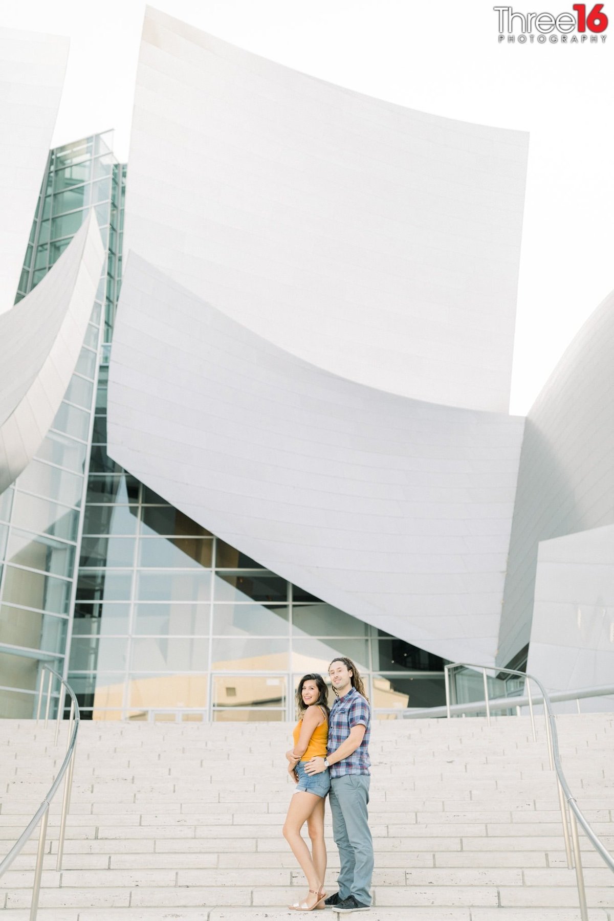 Groom to be holds his Bride from behind on the steps of the Walt Disney Concert Hall