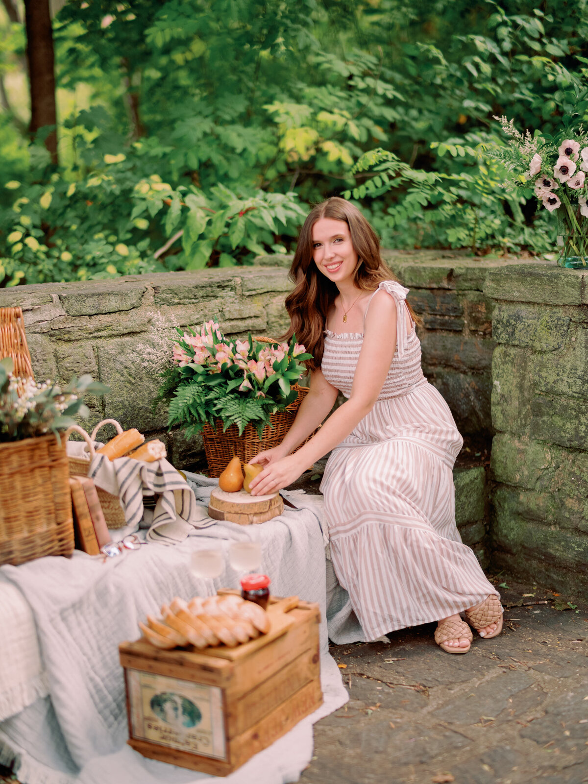 A person sits on a chair with fruit in front of them outdoors.
