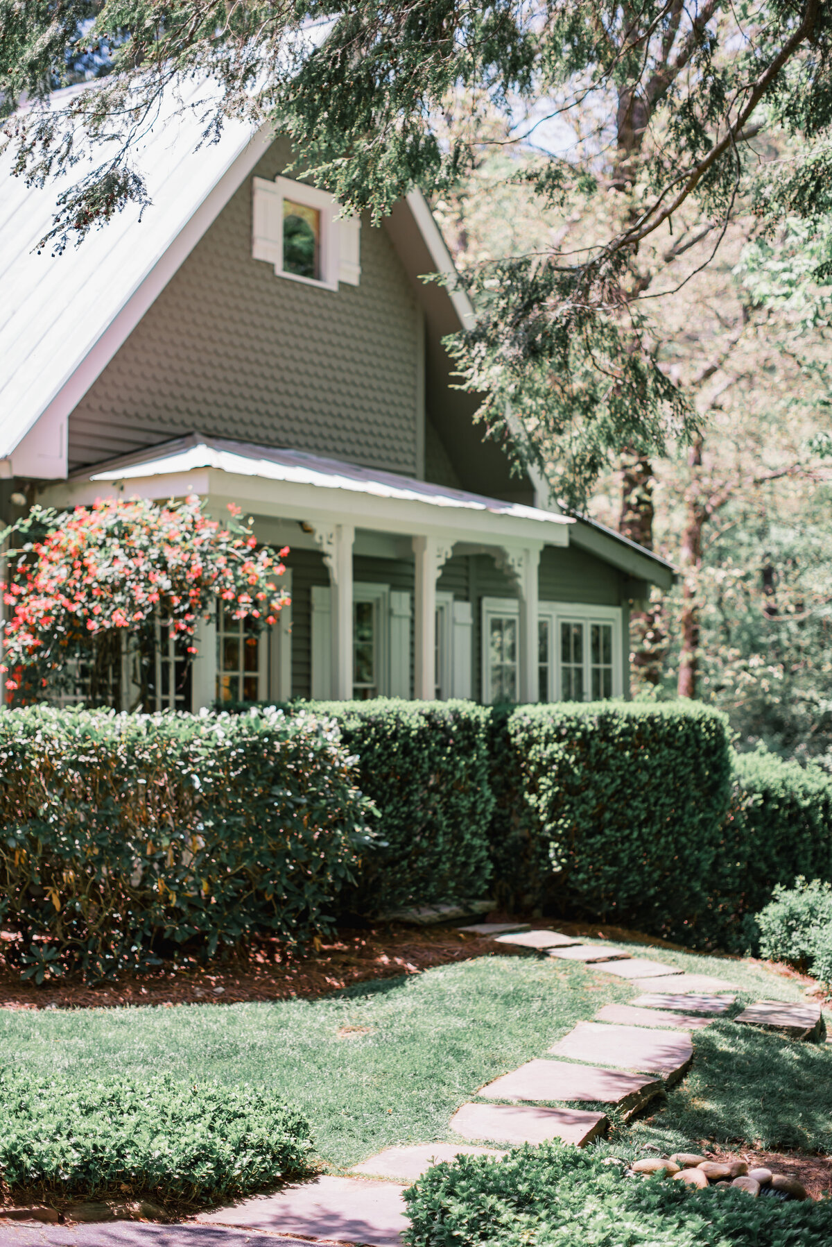  Charming cottage at Old Edwards Inn in Highlands, NC surrounded by lush greenery, used as a getting-ready location for a wedding.
