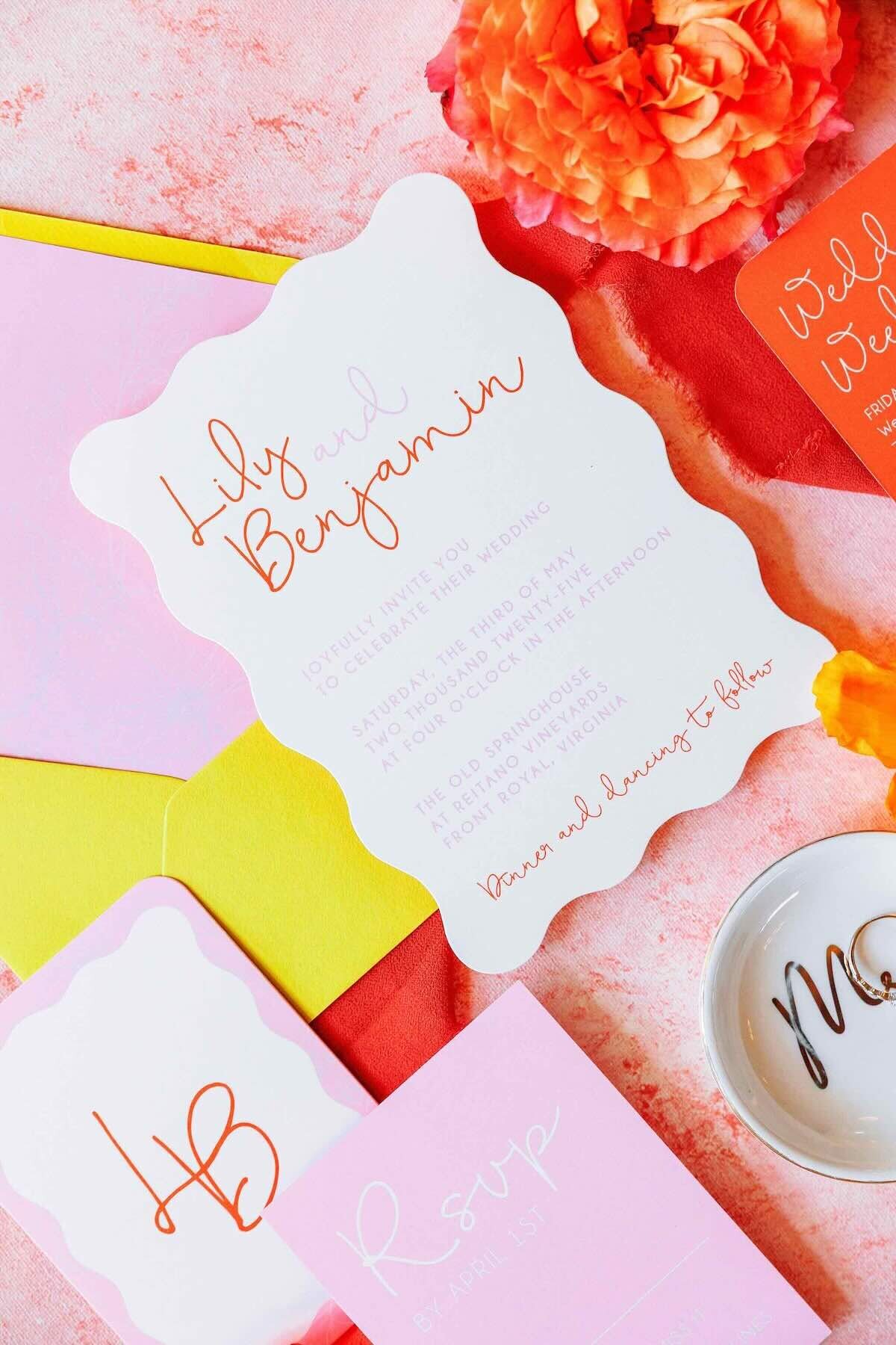 Playful invitation flatlay in pink, orange, and yellow with scalloped edges and bold pops of color.