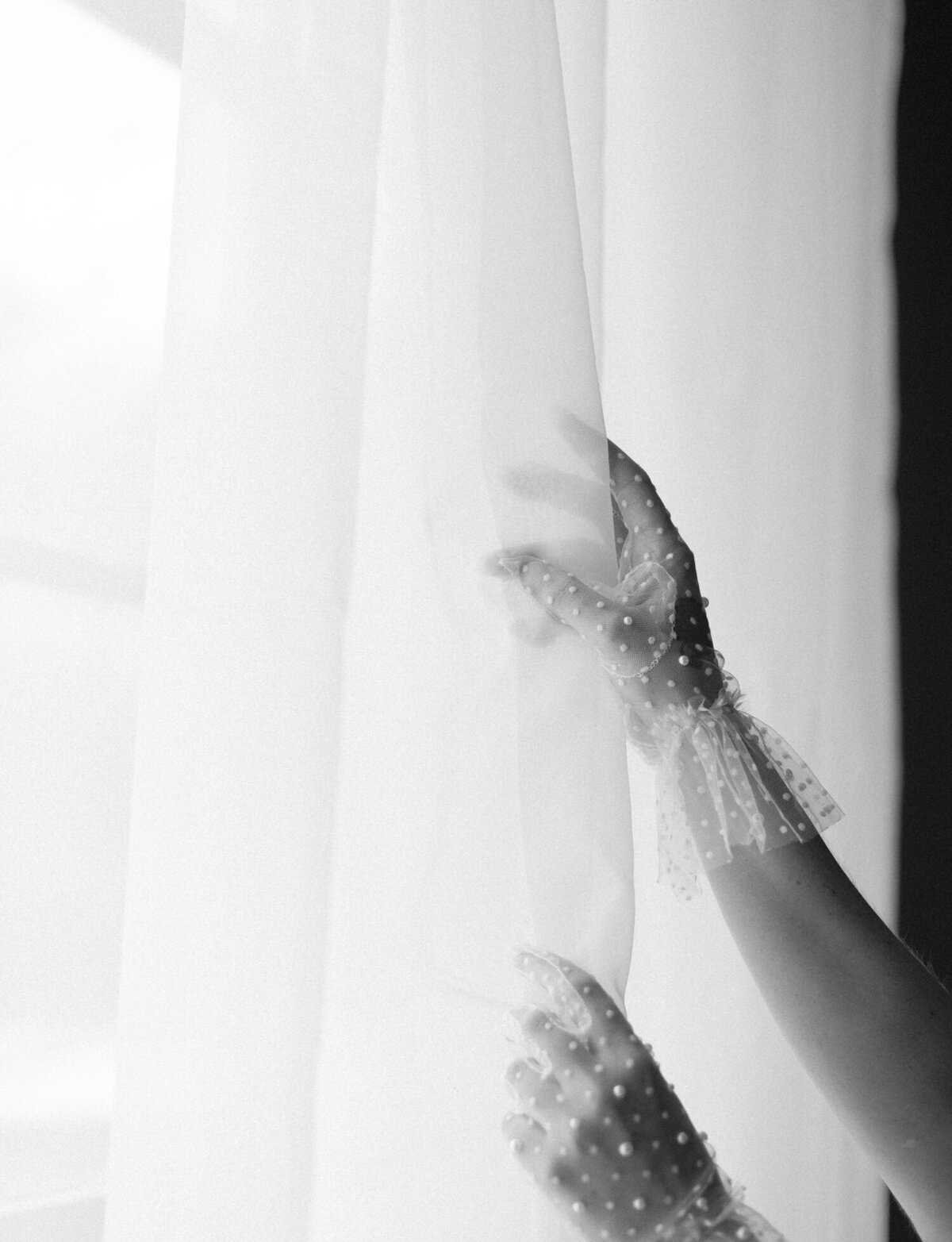 hands with pearl studded tulle gloves reach for sheer curtains, florist brand photos in Michigan