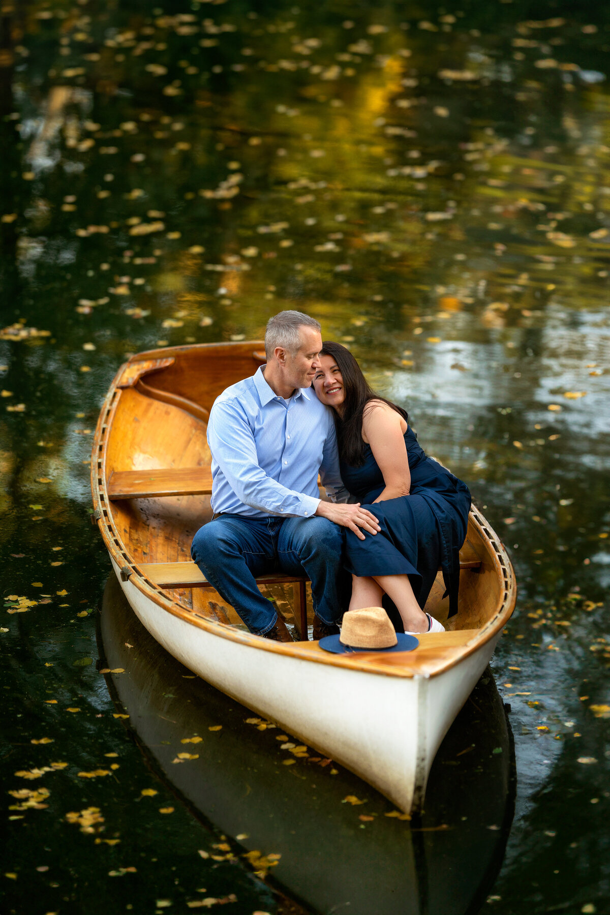 Engaged couple in the middle of the lake in a small wooden boat