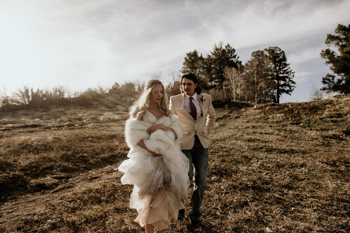 bride and groom walking down a hill together