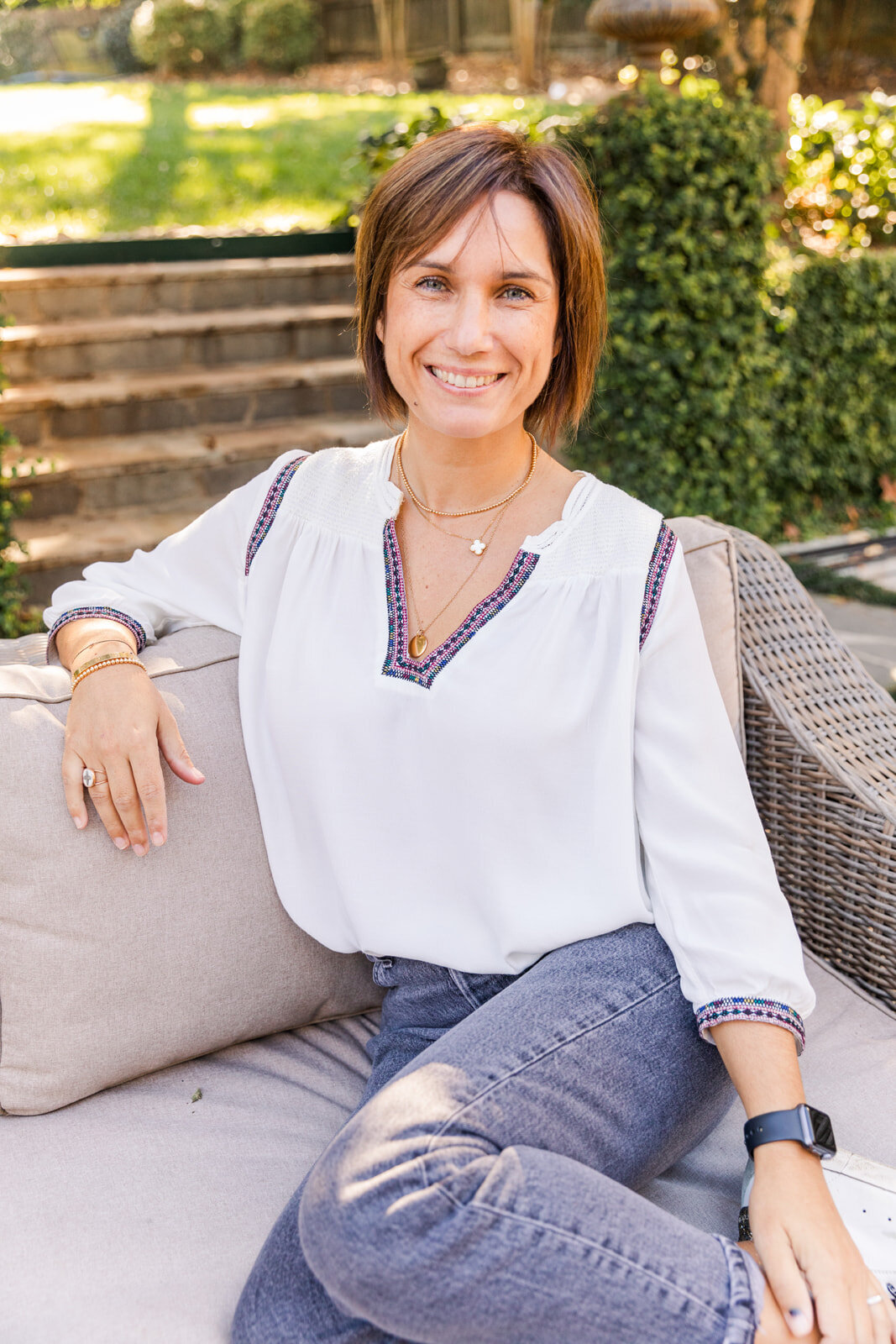 woman in jeans and whit top casually sitting on a outside sofa