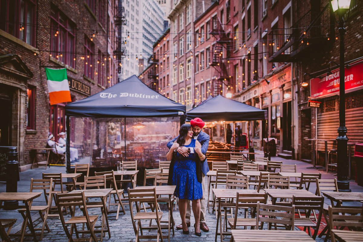 A couple sharing a moment standing in the middle of stone street in downtown manhattan new york city during their engagement session