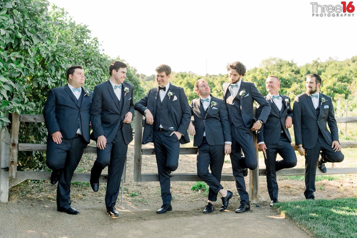 Groom and Groomsmen hanging out before the wedding against a ranch-style fence