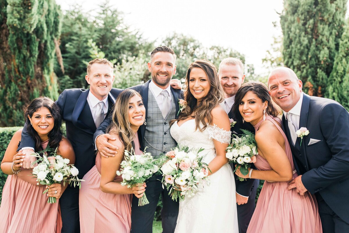 Fun, relaxed bridal party group photo at the Harbour View Hotel in Sandbanks. Summery blush pink Bridesmaids dresses and navy blue Groomsmen suits.