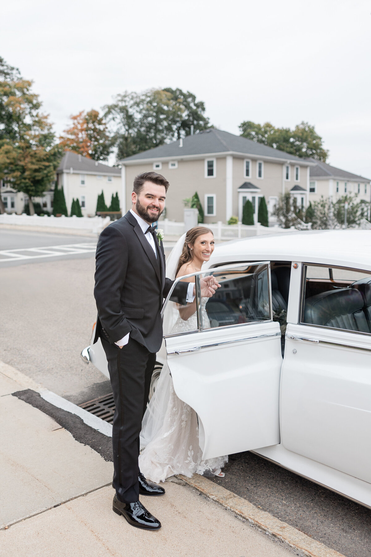 A groom helping his bride into a vintage Rolls Royce