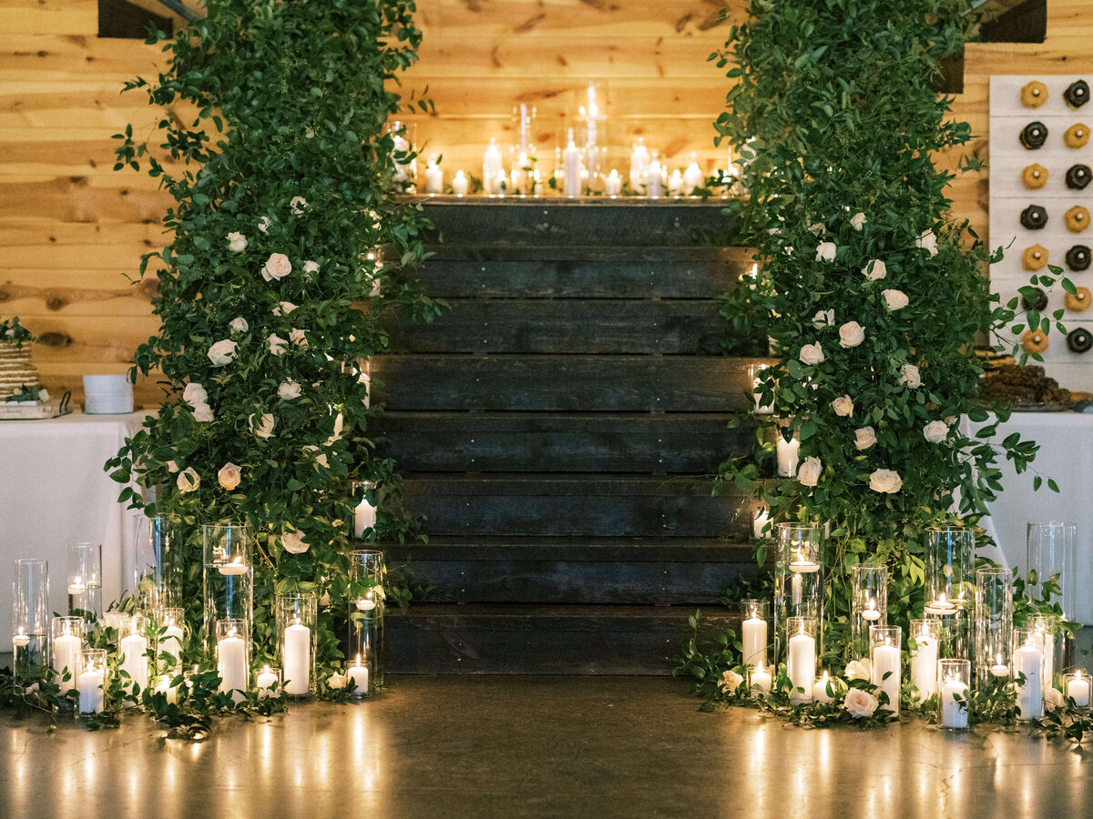 Candlelit staircase with lush greenery and white roses at rustic barn wedding venue in Texas